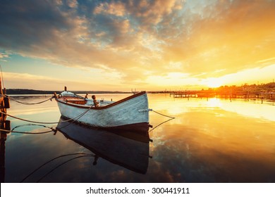 Boat on lake with a reflection in the water at sunset - Powered by Shutterstock