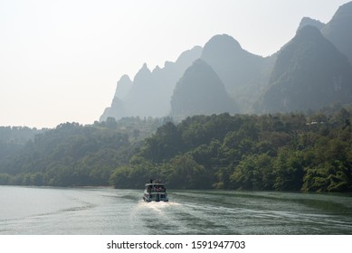 Boat on Li river cruise and karst formation mountain landscape in the fog between Guiling and Yangshuo, Guangxi province, China