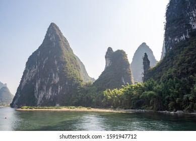 Boat on Li river cruise and karst formation mountain landscape in the fog between Guiling and Yangshuo, Guangxi province, China