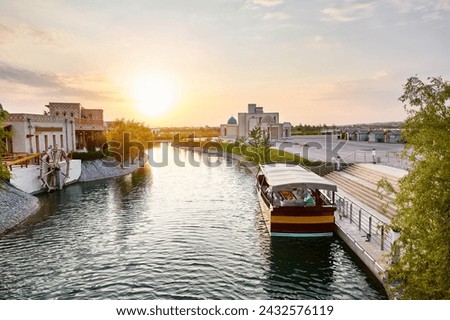 Boat on the pier at water channel Samarkand Eternal city Boqiy Shahar Registan complex at sunset sky background.