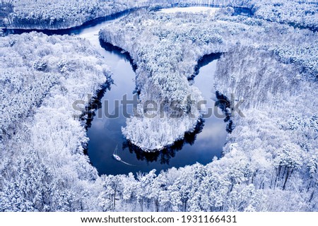 Boat on winter river. Extreme Sport in winter. Sailing between snowy forest. Aerial view of nature in Poland