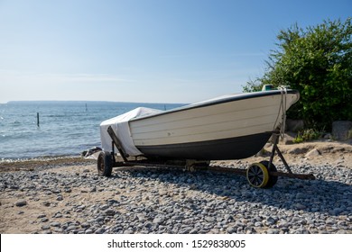 Boat parked on a trailer at the beach in summer, it's dry and likely about to be used