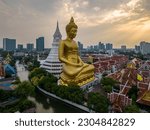 A boat was passing Big Buddha statue (Phra Buddha Dhammakaya Thepmongkhon ) in Wat Pak Nam Phasi Charoen temple located by the river during sunset.