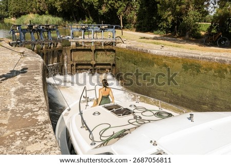 Boat passing through a river lock on the Canal du Midi in southern France. Navigation through a river lock with flowing water, UNESCO World Heritage site.