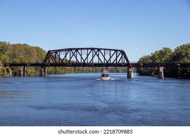 Boat passing under an old steel railway bridge on the Erie Canal
