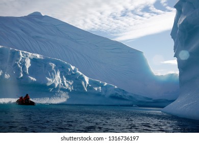 Boat With People, Sailing Next To Great Iceberg Walls In Antartica.