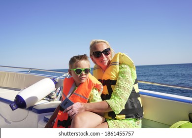 Boat ride on the sea along the rocky shore. Mother and son on a boat trip. Turquoise water and blue sky on a Sunny day.