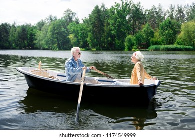 Boat Ride. Stylish Appealing Elderly Wife Wearing Yellow Shirt Feeling Amazing Sitting In Boat With Husband