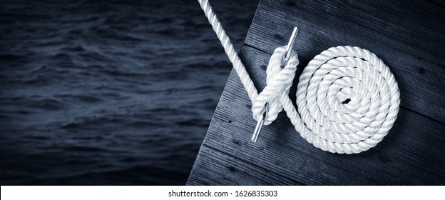 Boat Rope Secured To Cleat On Wooden Dock With Dark Water Below - Shutterstock ID 1626835303