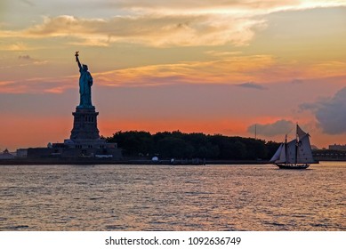 A boat sailing in front of the Statue of Liberty at sunset in New York City USA