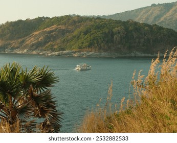 A boat is sailing on a lake with a lush green hillside in the background. The scene is peaceful and serene, with the boat moving slowly through the calm waters - Powered by Shutterstock