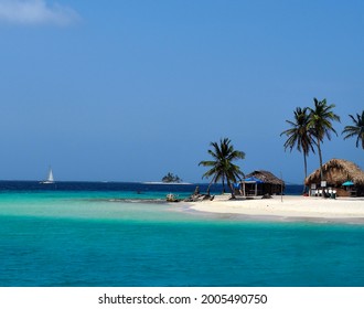 Boat sailing past a small beach and huts in the Caribbean - Powered by Shutterstock