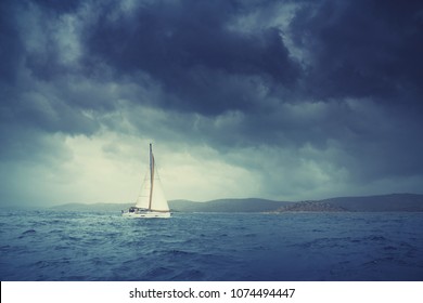 Boat Sailing In The Upcomming Storm. Sailboat In Bad Weather Sail At Opened Sea. Sailing Yacht Under Heavy Cloud Sky.