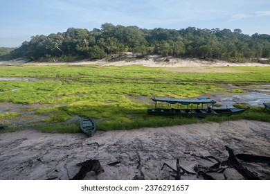 Boat stranded on dry river in extreme drought in the Amazon Rainforest, the largest tropical forest in the world. Concept of climate change, global warming, environment, ecology, disaster, weather.