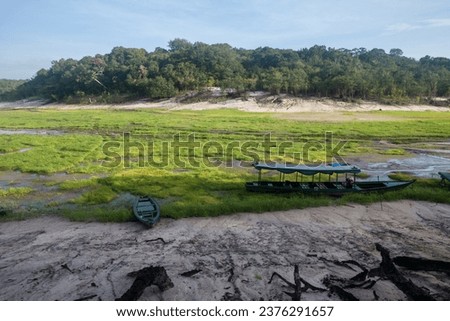 Boat stranded on dry river in extreme drought in the Amazon Rainforest, the largest tropical forest in the world. Concept of climate change, global warming, environment, ecology, disaster, weather.