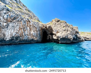 A boat tour near Santa Maria di Leuca reveals a sunlit sea cave entrance. Turquoise waters and rugged cliffs under a clear blue sky showcase the beauty of coastal exploration and nature’s artistry. - Powered by Shutterstock