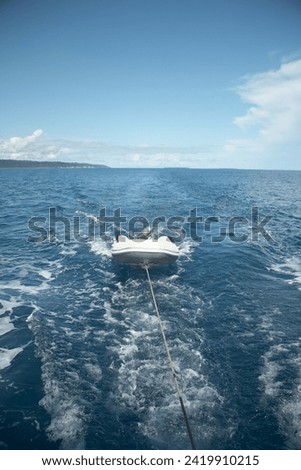 boat towing a dingy in blue ocean water