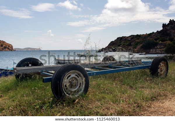 A boat trailer and fishing\
boats in the beach in the island of Patmos, Greece in summer\
time