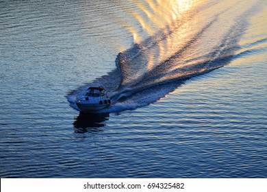 Boat wake on water surface in sunset light