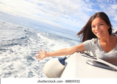 Boat woman smiling happy looking at the sea sailing by. Asian / Caucasian female model.