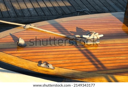 Boat at a wooden dock in harbor. Boat knot equipment. Mooring knot, hitch on wooden desk. Yacht detail. Travel and lifestyle view. Rigging equipment. Varnish wooden desk of boat. Landing stage.