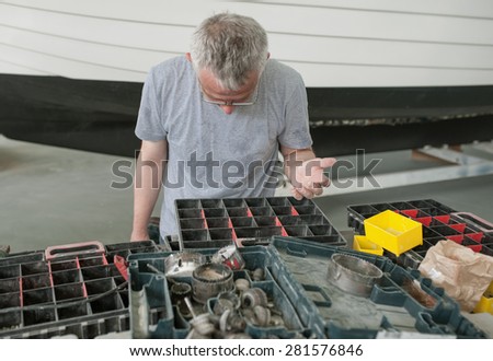 boat worker is looking for his corresponding tool.