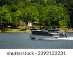 Boater on pontoon boat enjoying summer day on Lake. Pontoon party boat cruising on freshwater lake.