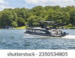 Boaters on pontoon boat enjoying summer day on Lake. Pontoon party boat cruising on freshwater lake.