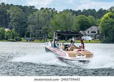 Boaters on red wakeboard ski boat enjoying summer day on freshwater lake. - Powered by Shutterstock