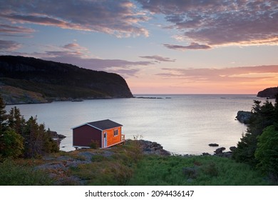Boathouse overlooking calm bay at sunrise - Shutterstock ID 2094436147