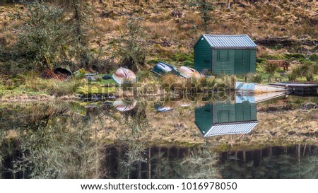 The Boathouse reflected in Allt a' Chip Dhuibh Lochan in the hills south of Loch Venachar, in the Trossachs, in the Scottish Highlands