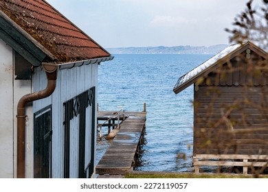 Boathouses and jetty in Seeshaupt in Bavaria at Lake Starnberg on a slightly cloudy winter day