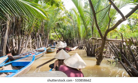 Boating on a dirty river with conical hats in the Mekong Delta, Vietnam