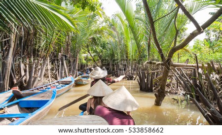 Boating on a dirty river with conical hats in the Mekong Delta, Vietnam