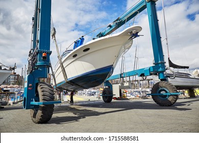 Boat-lift is lifting and transporting a boat in a boatyard for maintenance, repairs and cleaning in a sunny day