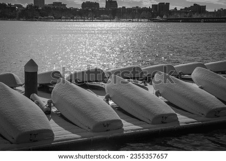 The boats covered in snow along the Charles river in Boston in black and white.