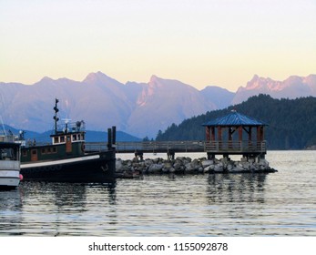 Boats docked as the sun goes down in Gibsons, British Columbia, along the Sunshine Coast. Water is calm and tranquil.          