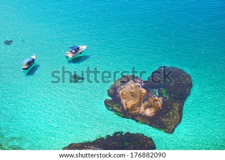 boats floating near the stone in the shape of heart. Romantic island lovers