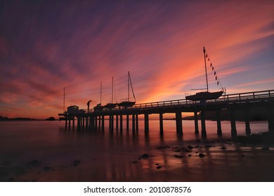 Boats In A Harbor On A Dock In Moss Landing And Pebble Beach California Still Water Cove Sunset Sunrise Soft Long Exposure Pink Orange Clouds Making A Reflection On The Sea Ocean Bay Luxury Vacation