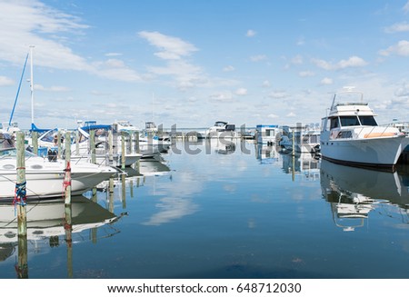 Boats and luxury yachts parked at docks and on hoists in a private yachting club. Long Beach Island, New Jersey ocean boating background