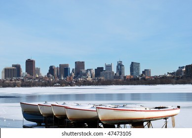 boats on frozen charles river overlooking boston skyline in the winter