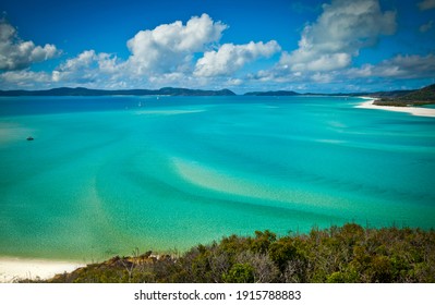 The boats scattered across turquoise waters of Hill Inlet in Whitsundays, Queensland, Australia. Swirling ribbons of blue and azure from white sands of Whitehaven beach and forest-covered islands.
