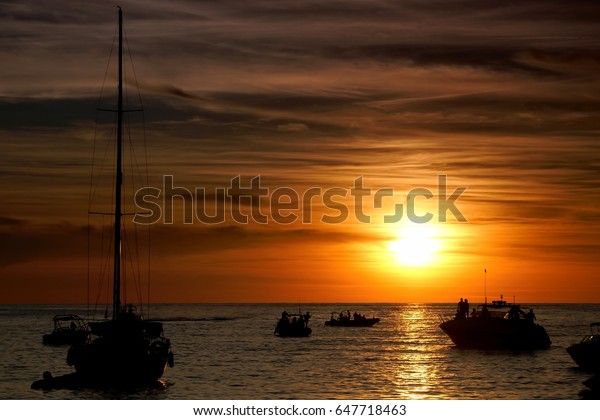 Boats silhouetted in the sunset on\
Sunset Strip at Sant Antoni de Portmany, Ibiza,\
Spain