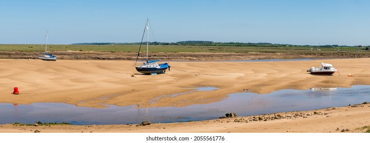 Boats at Wells next the Sea on the beach at low tide in June 2021 on the North Norfolk coast.