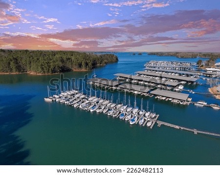 Boats and yachts docked and sailing in the marina on Lake Lanier with lush green trees and and powerful clouds at sunset in Cummings Georgia USA