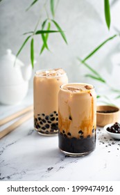 Boba milk tea with brown sugar syrup in a tall glass with ice on marble table