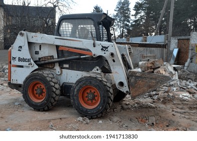 A bobcat skid steer loader transports work on old house demolition. 23 March 2021. Kiev Region, Ukraine