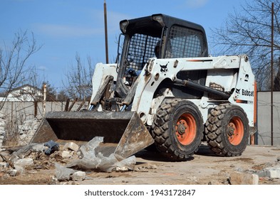A Bobcat skid steer loader transports work on old house demolition. 24 March 2021. Kiev Region, Ukraine