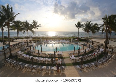 BOCA RATON, FLORIDA/USA - APRIL 1 2018:  Bathers and loungers enjoy a beautiful sunrise flanked by palm trees overlooking the Atlantic Ocean at the pool deck of Boca Beach Club.
