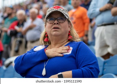 Boca Raton, Florida/USA - December 21, 2019: Florida Atlantic Owls Vs SMU Mustangs. Woman In Blue Football Jersey Holding Right Hand In A Chest And Singing US National Anthem.